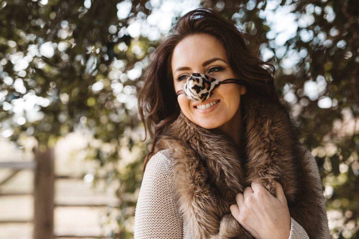 A woman wearing a snow leopard print faux-fur nose warmer outdoors